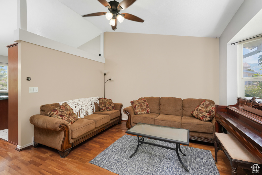 Living room with wood-type flooring, ceiling fan, and lofted ceiling