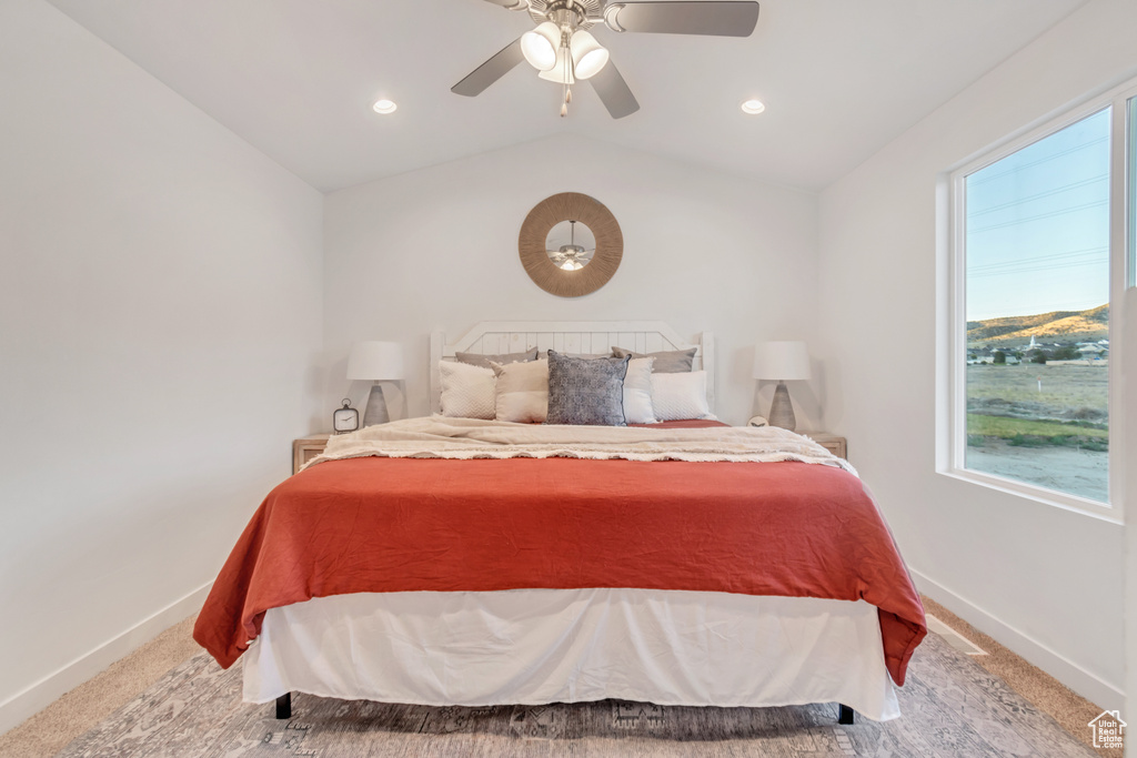 Carpeted bedroom with ceiling fan and vaulted ceiling