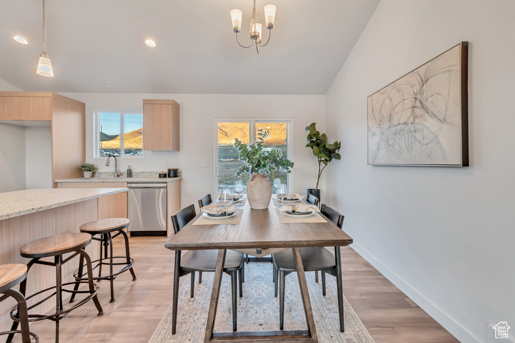 Dining space with sink, light hardwood / wood-style flooring, an inviting chandelier, and lofted ceiling