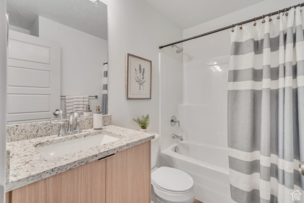 Full bathroom with vanity, shower / bathtub combination with curtain, and toilet