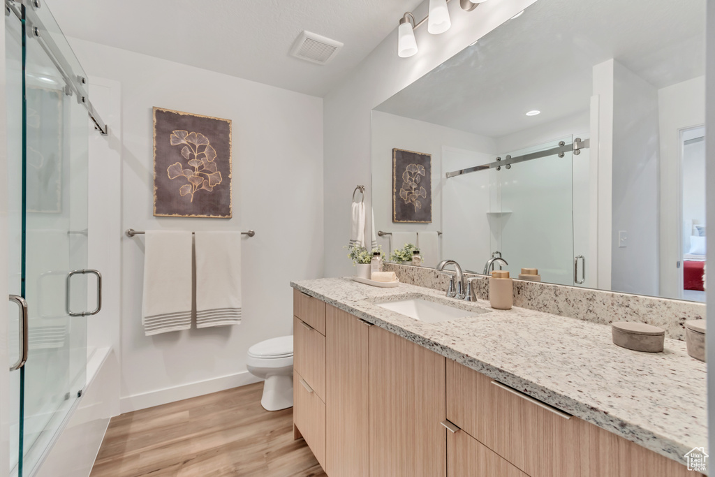 Bathroom featuring vanity, hardwood / wood-style flooring, and toilet