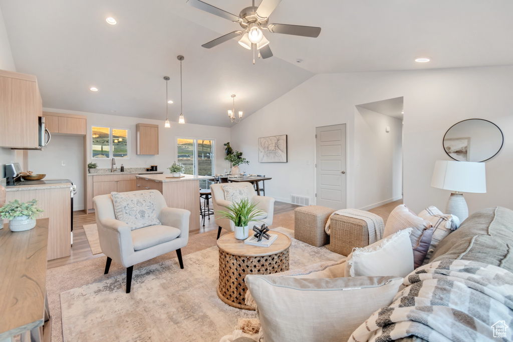 Living room featuring light hardwood / wood-style floors, sink, lofted ceiling, and ceiling fan with notable chandelier