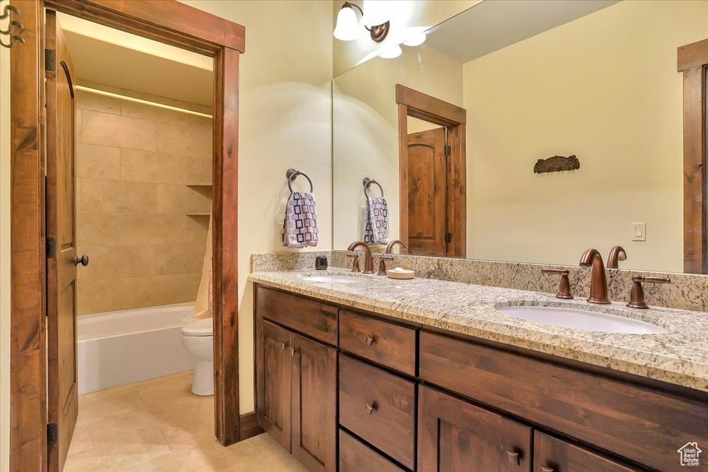 Full bathroom featuring tile floors, tiled shower / bath, double vanity, and toilet