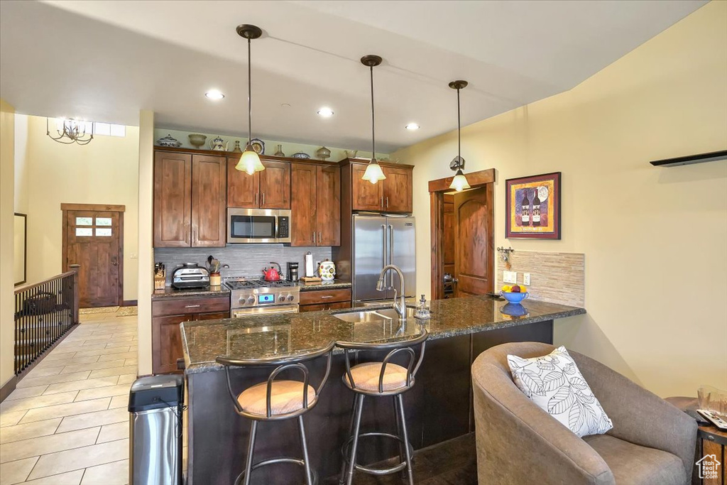Kitchen with decorative light fixtures, tasteful backsplash, a breakfast bar area, sink, and high quality appliances