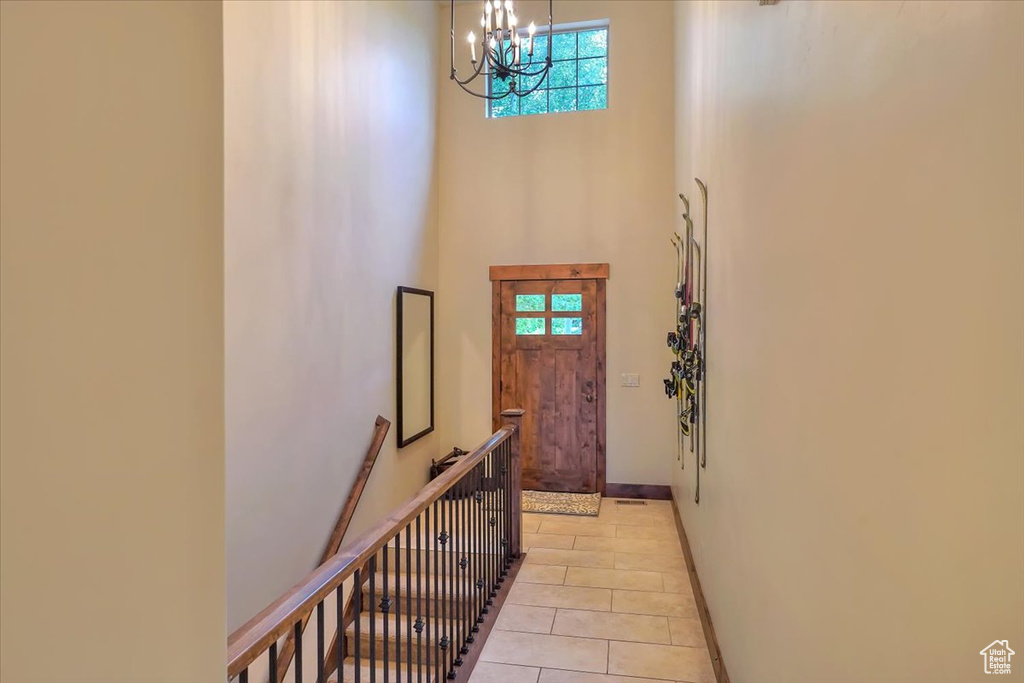 Doorway featuring a high ceiling, light tile floors, and an inviting chandelier