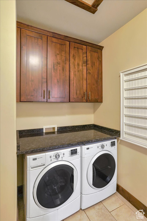 Laundry area featuring washer and dryer, cabinets, light tile floors, and washer hookup