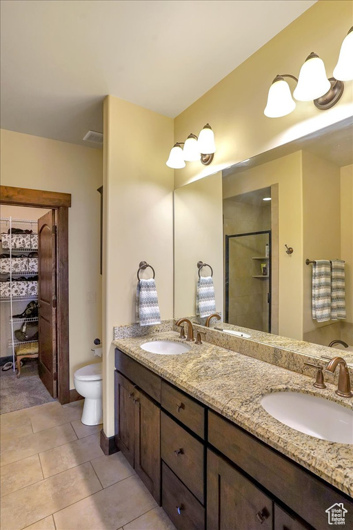 Bathroom with walk in shower, tile floors, large vanity, toilet, and dual sinks