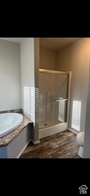 Bathroom with hardwood / wood-style flooring, plus walk in shower, and toilet