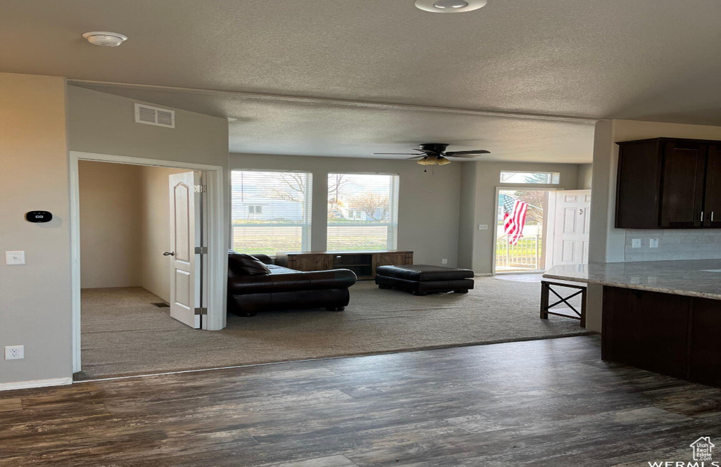 Unfurnished living room with dark hardwood / wood-style floors, ceiling fan, and a textured ceiling