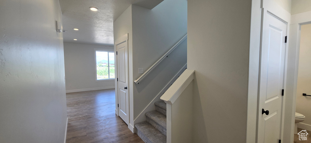 Stairs featuring a textured ceiling and wood-type flooring