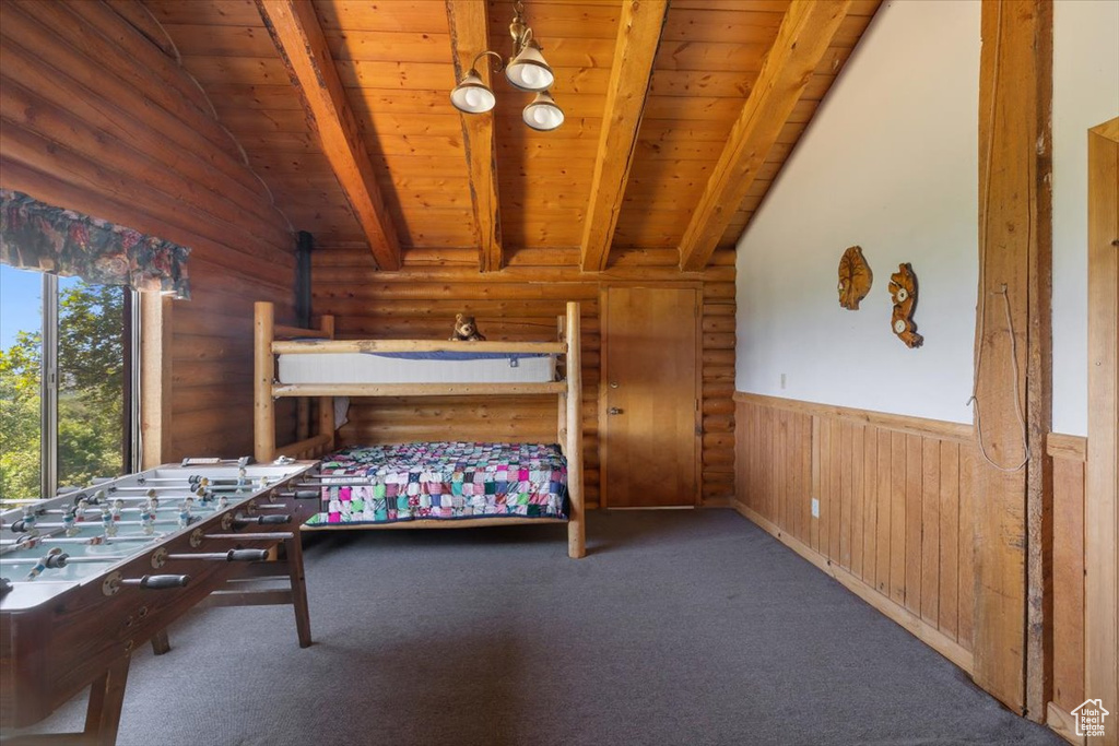 Unfurnished bedroom with wooden ceiling, vaulted ceiling with beams, log walls, and carpet