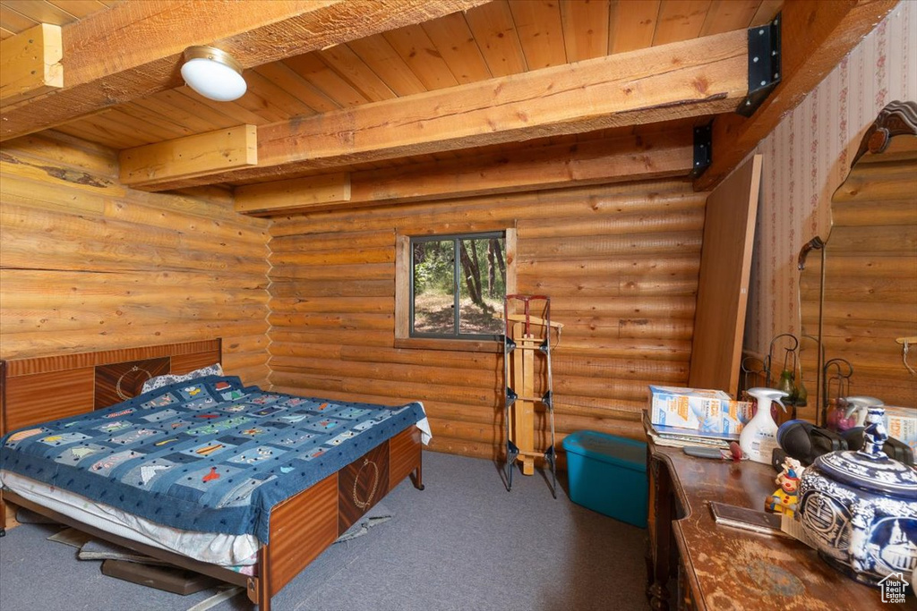 Bedroom featuring carpet flooring, wooden ceiling, rustic walls, and beam ceiling