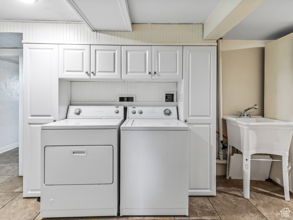 Laundry area with cabinets, washer hookup, light tile floors, and washing machine and dryer