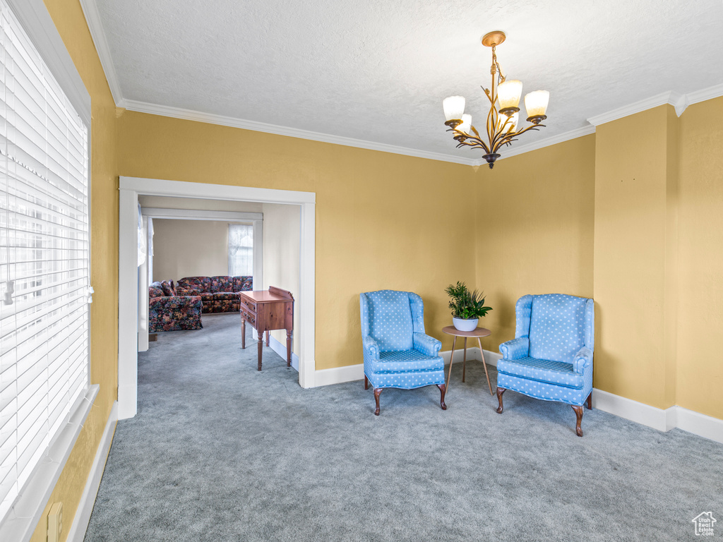 Living area featuring ornamental molding, carpet flooring, and a chandelier