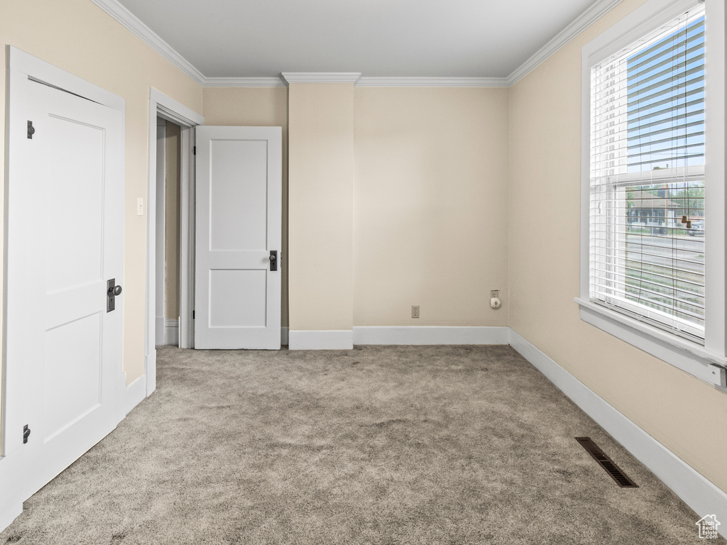 Empty room with light colored carpet and crown molding