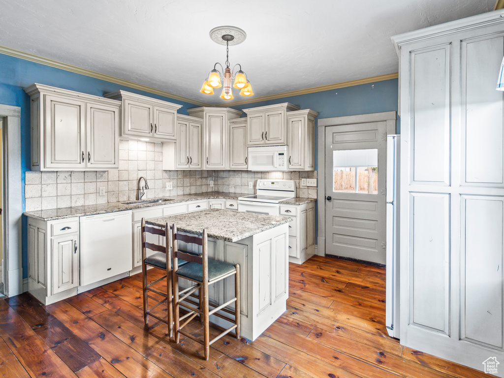 Kitchen with dark hardwood / wood-style floors, tasteful backsplash, white appliances, a center island, and sink