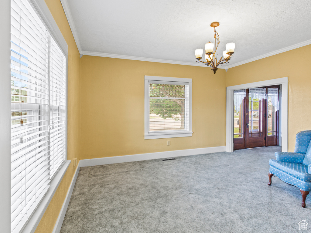 Unfurnished room featuring ornamental molding, carpet, and an inviting chandelier