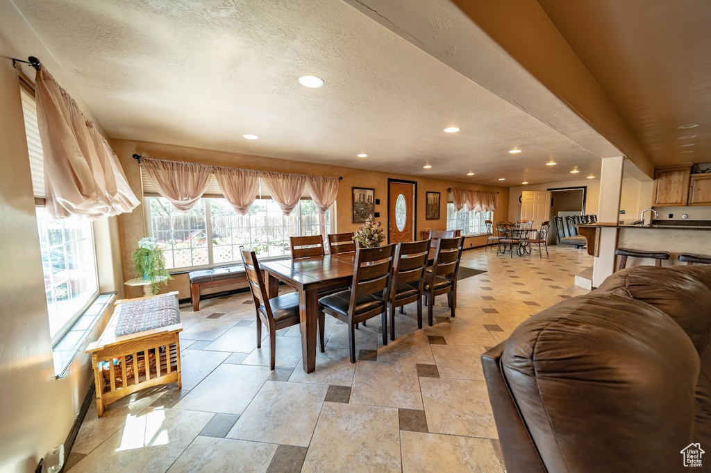 Dining area featuring sink, a textured ceiling, and light tile floors