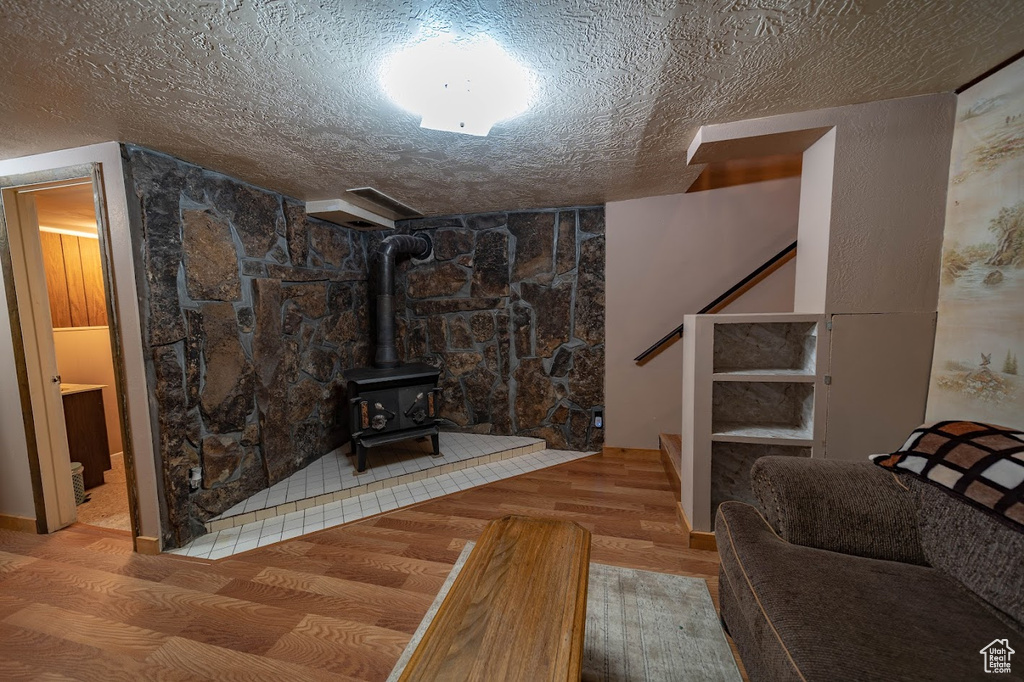 Living room featuring light hardwood / wood-style flooring, a textured ceiling, and a wood stove