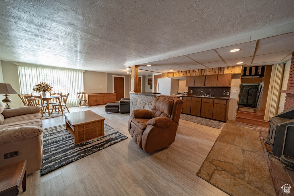 Living room featuring sink, ornate columns, brick wall, and light wood-type flooring