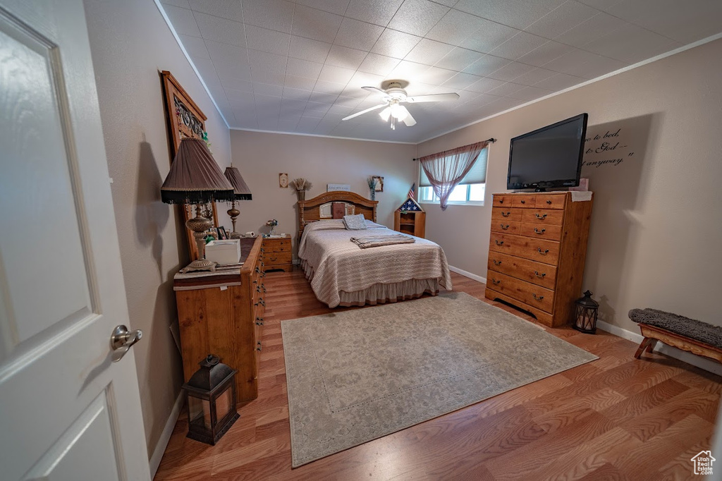 Bedroom featuring hardwood / wood-style floors, ornamental molding, and ceiling fan