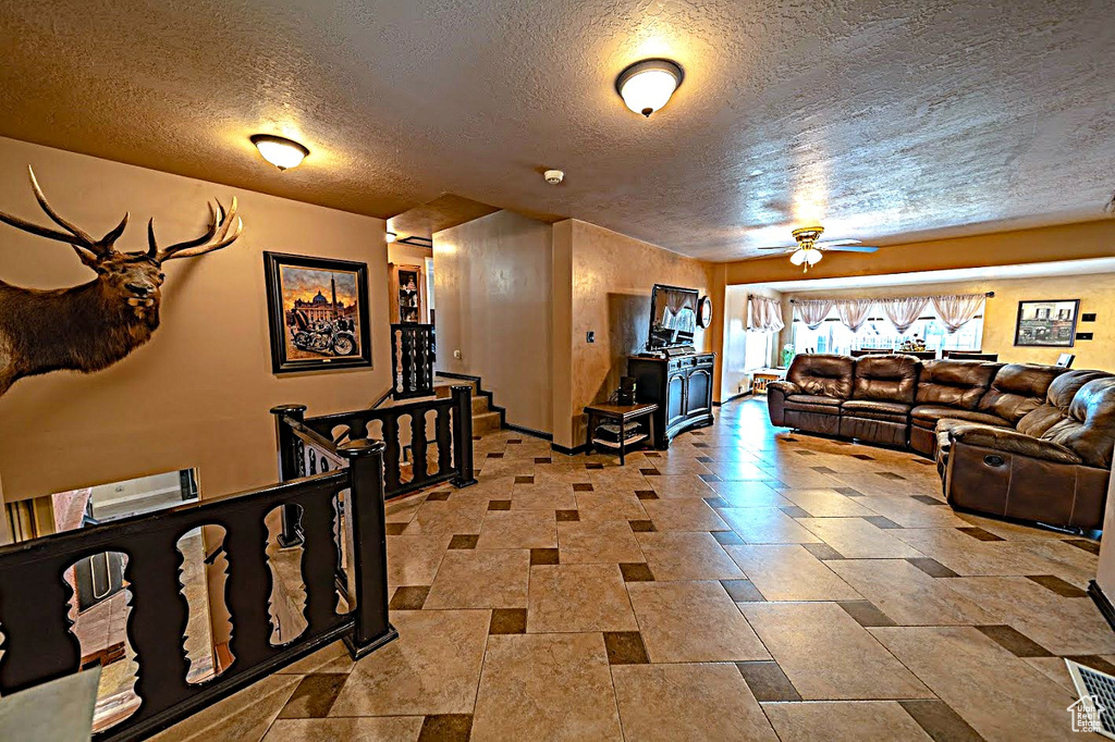 Tiled living room featuring ceiling fan and a textured ceiling