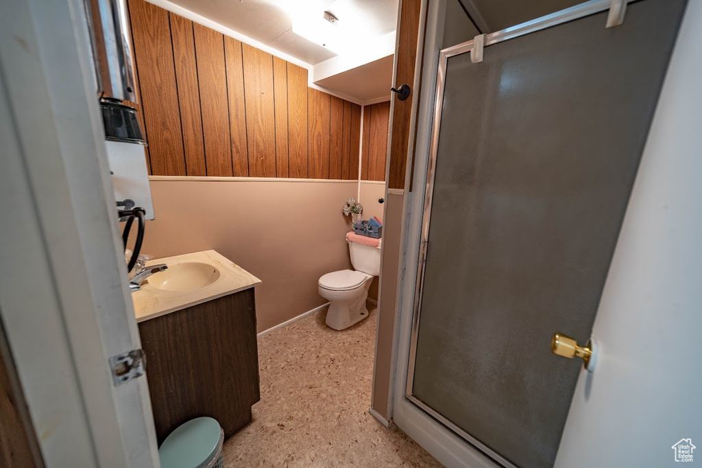 Bathroom with walk in shower, wooden walls, toilet, and vanity