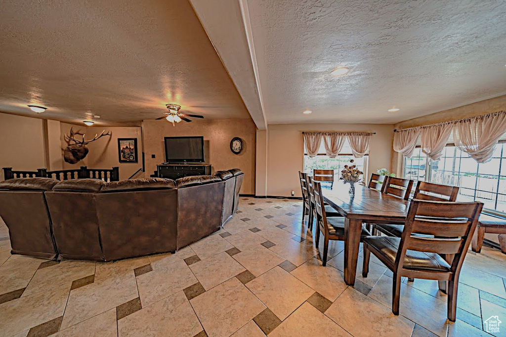 Dining room featuring ceiling fan, a textured ceiling, and light tile floors