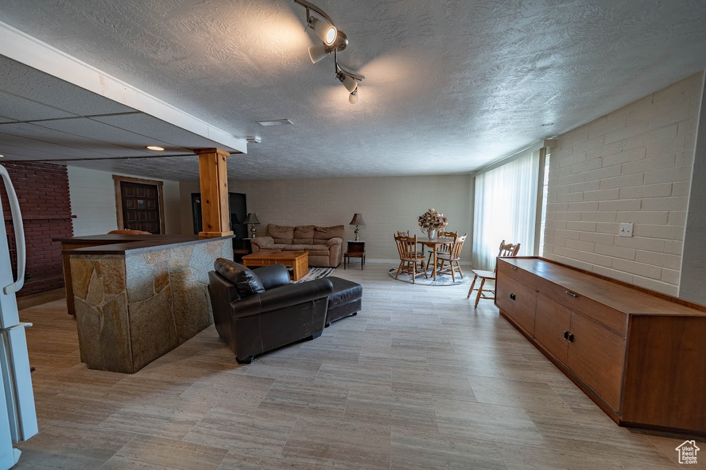 Living room featuring a textured ceiling and brick wall