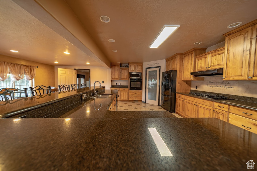 Kitchen with black appliances, sink, and light tile flooring