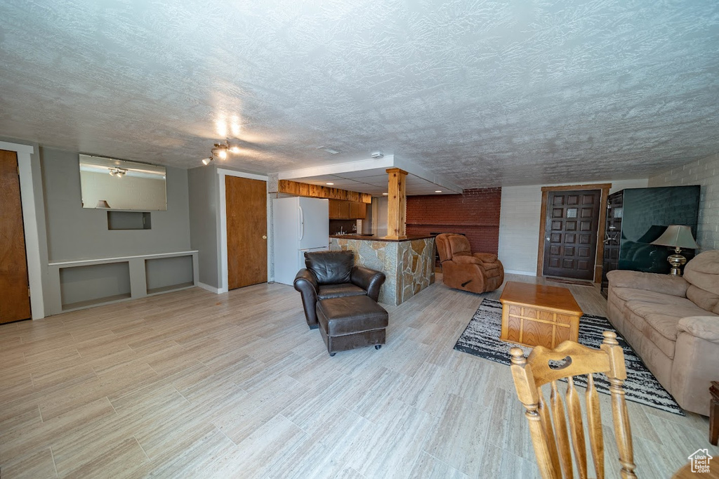 Living room featuring a textured ceiling and brick wall