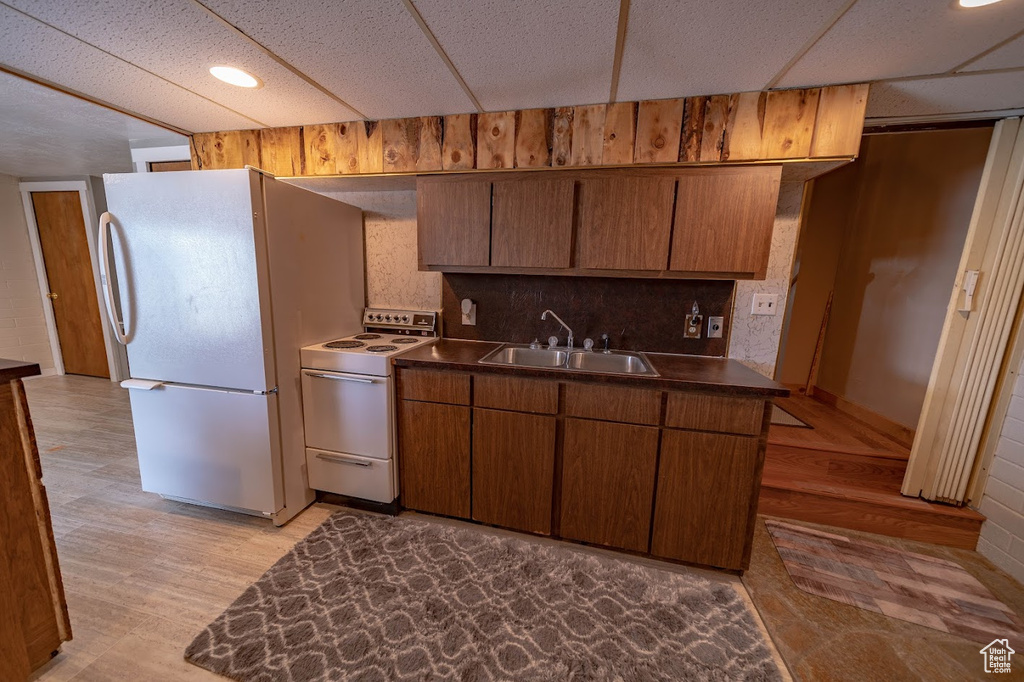 Kitchen featuring sink, light hardwood / wood-style flooring, white appliances, and backsplash