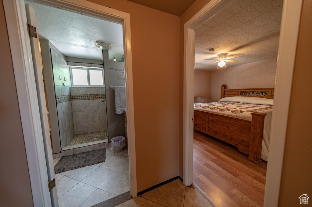 Bathroom featuring a tile shower, ceiling fan, hardwood / wood-style flooring, and a textured ceiling