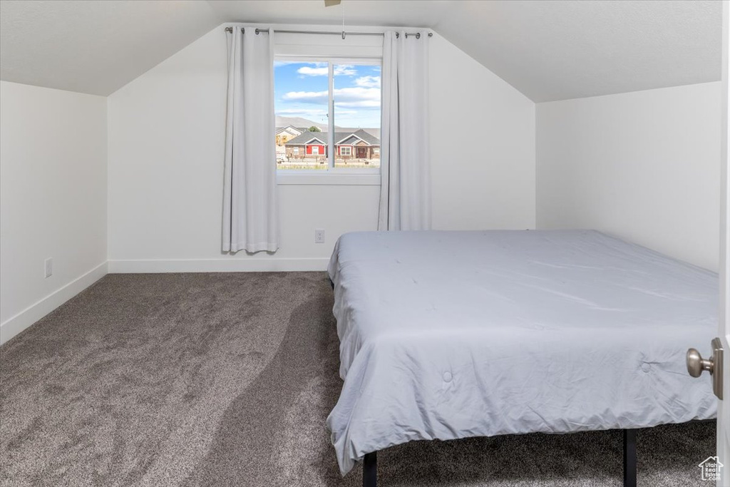 Bedroom with vaulted ceiling and carpet floors