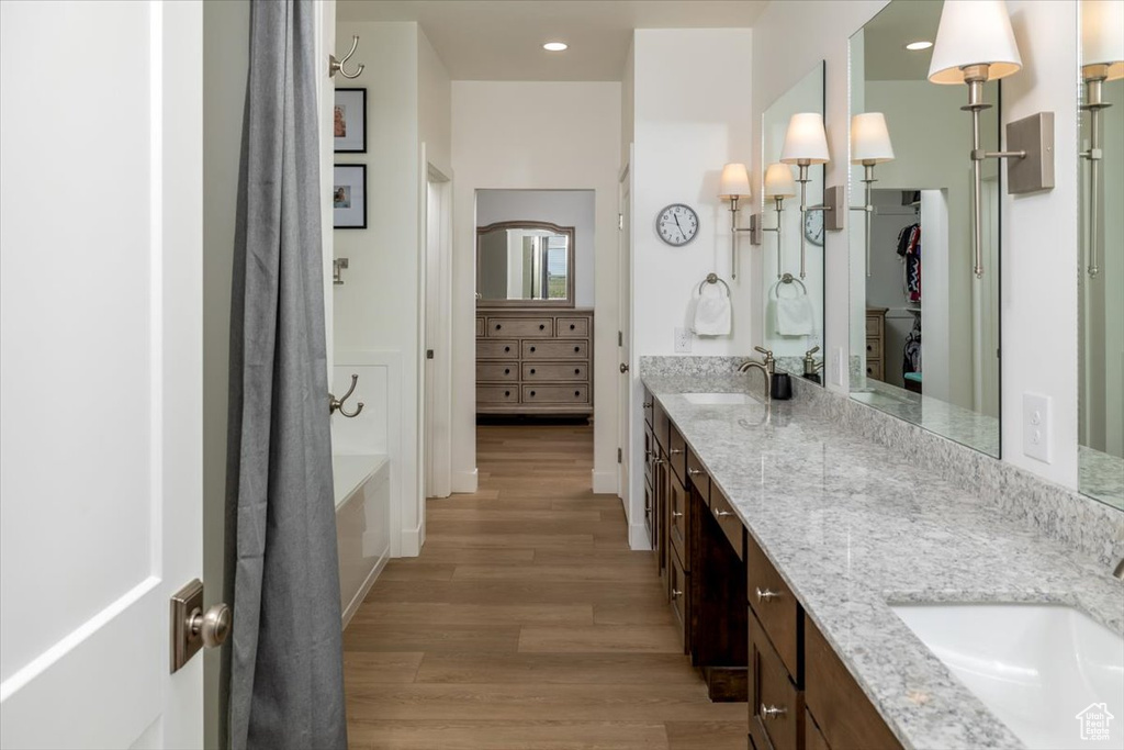 Bathroom with dual sinks, oversized vanity, and hardwood / wood-style flooring