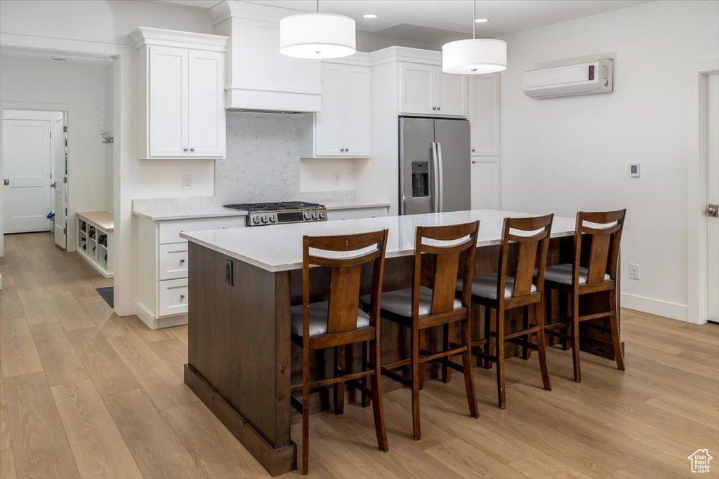 Kitchen featuring light hardwood / wood-style floors, stainless steel fridge with ice dispenser, a kitchen island, pendant lighting, and custom exhaust hood