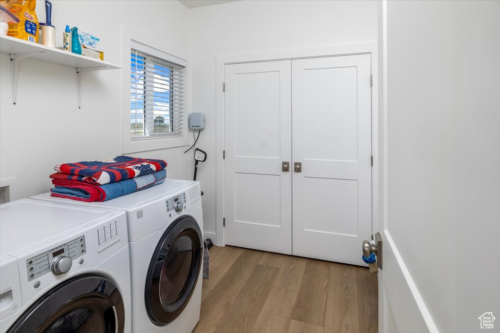 Clothes washing area featuring independent washer and dryer and light wood-type flooring