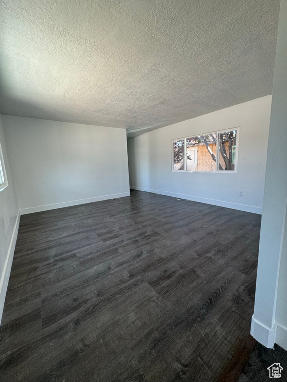 Spare room featuring dark wood-type flooring and a textured ceiling