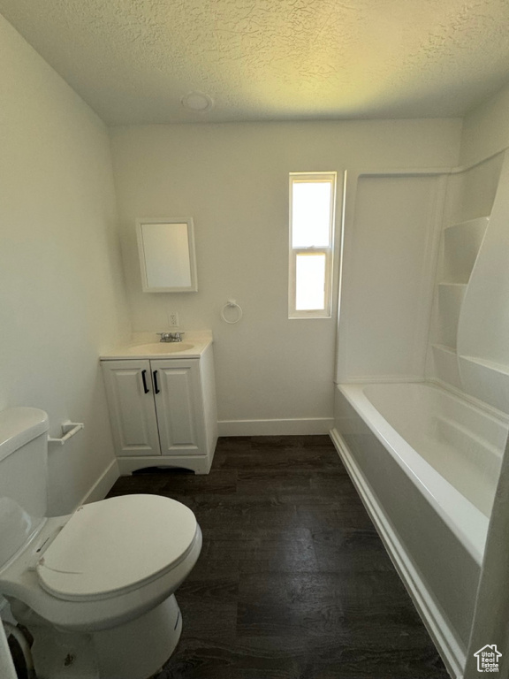 Full bathroom featuring a textured ceiling, washtub / shower combination, toilet, wood-type flooring, and oversized vanity