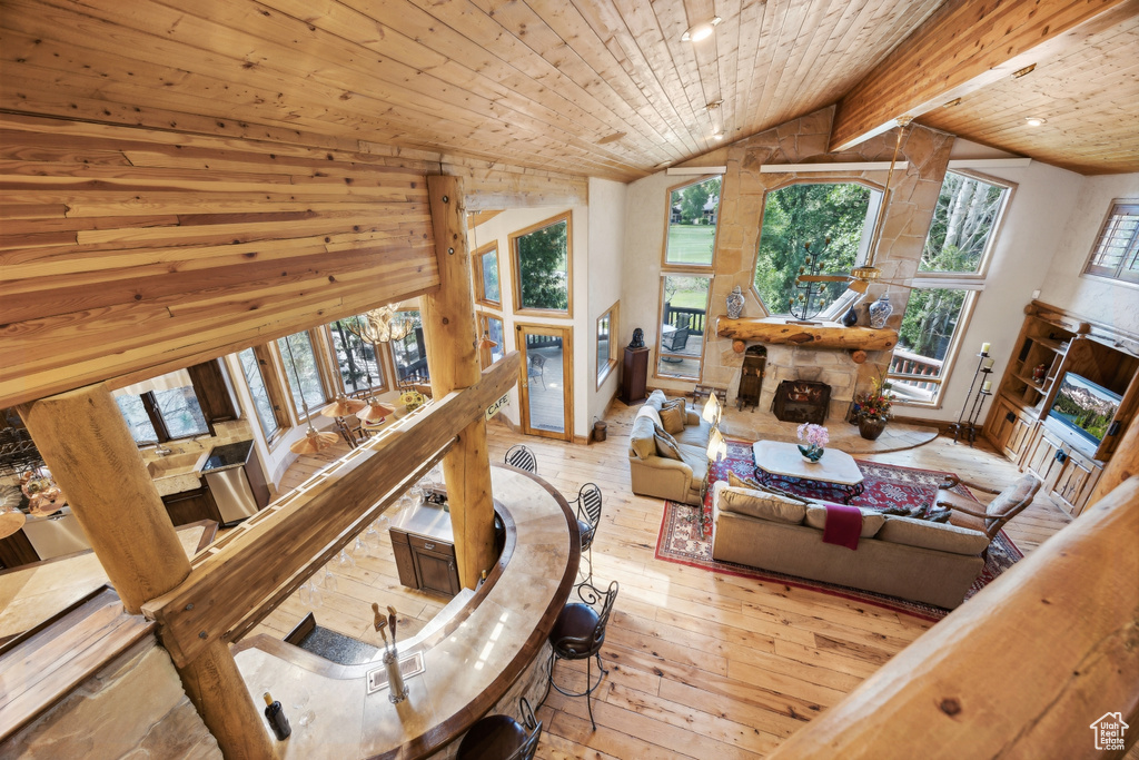 Living room featuring light hardwood / wood-style floors, wooden walls, vaulted ceiling with beams, and wooden ceiling