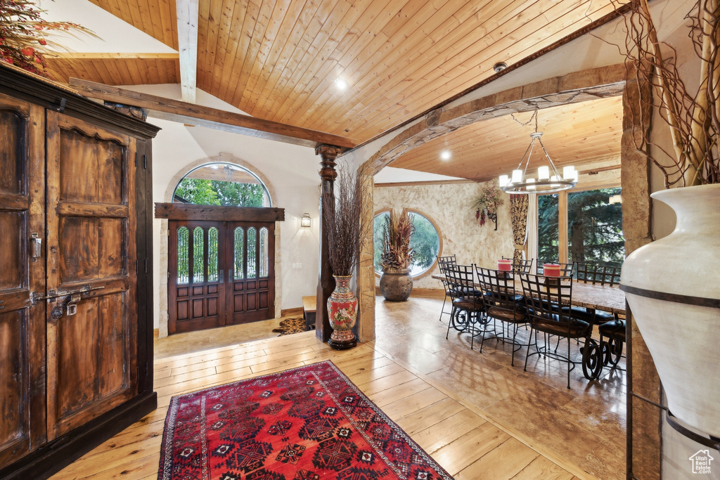 Entrance foyer featuring french doors, lofted ceiling with beams, light hardwood / wood-style flooring, a chandelier, and wood ceiling