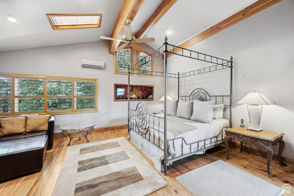 Bedroom featuring light hardwood / wood-style flooring, an AC wall unit, a skylight, ceiling fan, and beamed ceiling