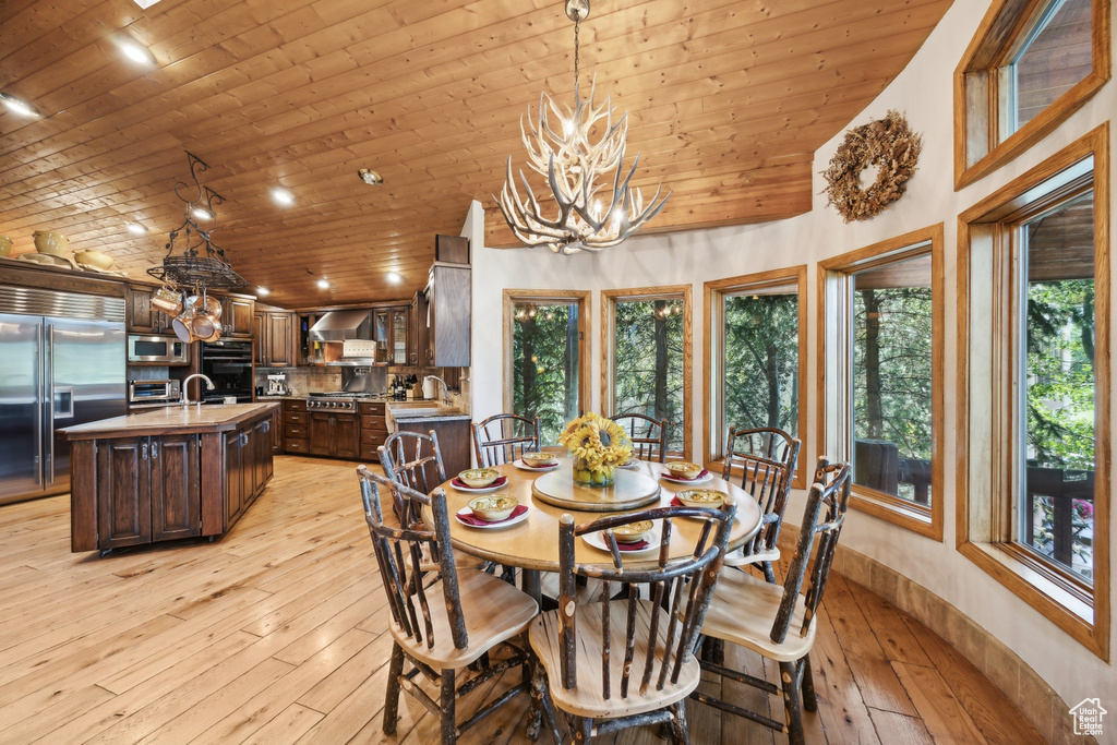 Dining space with a notable chandelier, a wealth of natural light, wood ceiling, and light wood-type flooring