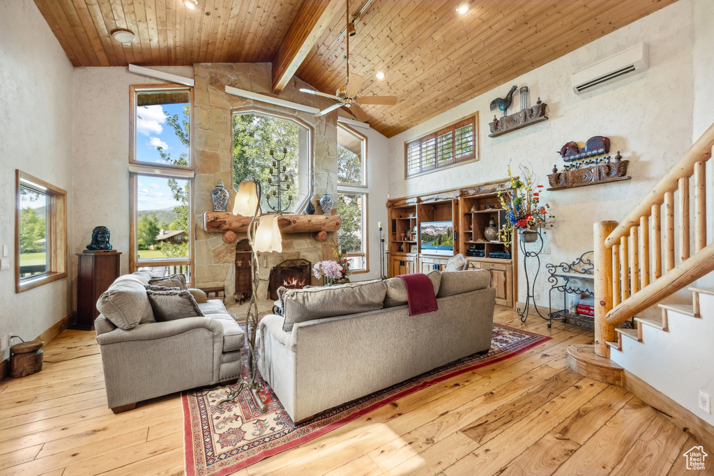 Living room with light hardwood / wood-style floors, a wall mounted air conditioner, ceiling fan, wooden ceiling, and high vaulted ceiling