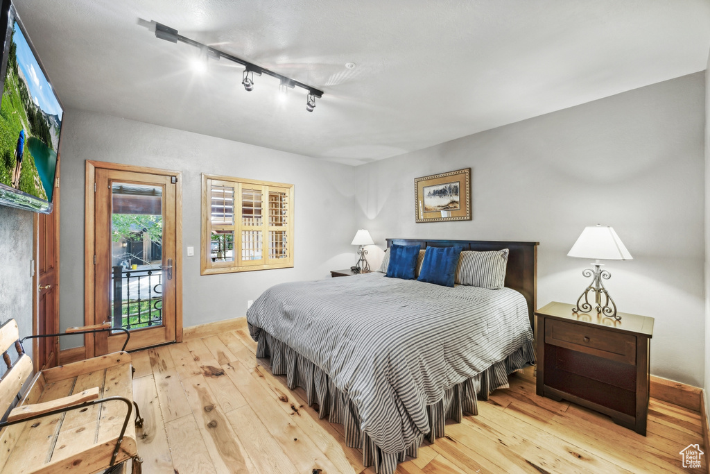 Bedroom featuring access to exterior, hardwood / wood-style floors, and track lighting