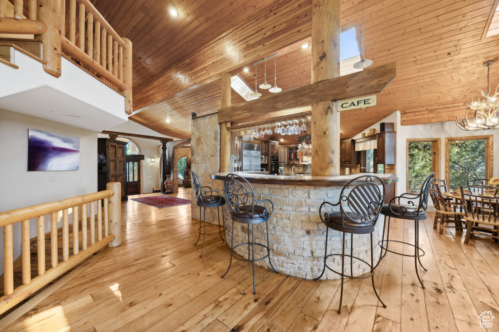 Kitchen featuring a breakfast bar, high vaulted ceiling, wood ceiling, and light hardwood / wood-style flooring