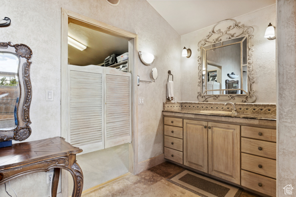 Bathroom featuring tile flooring, vaulted ceiling, and vanity