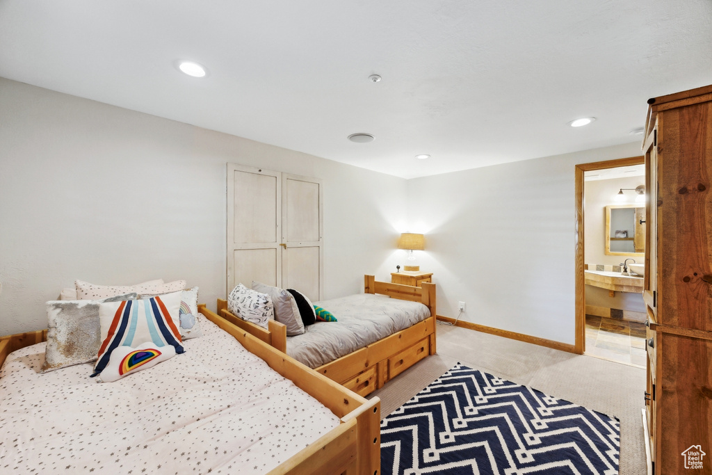 Bedroom featuring sink, connected bathroom, and light carpet