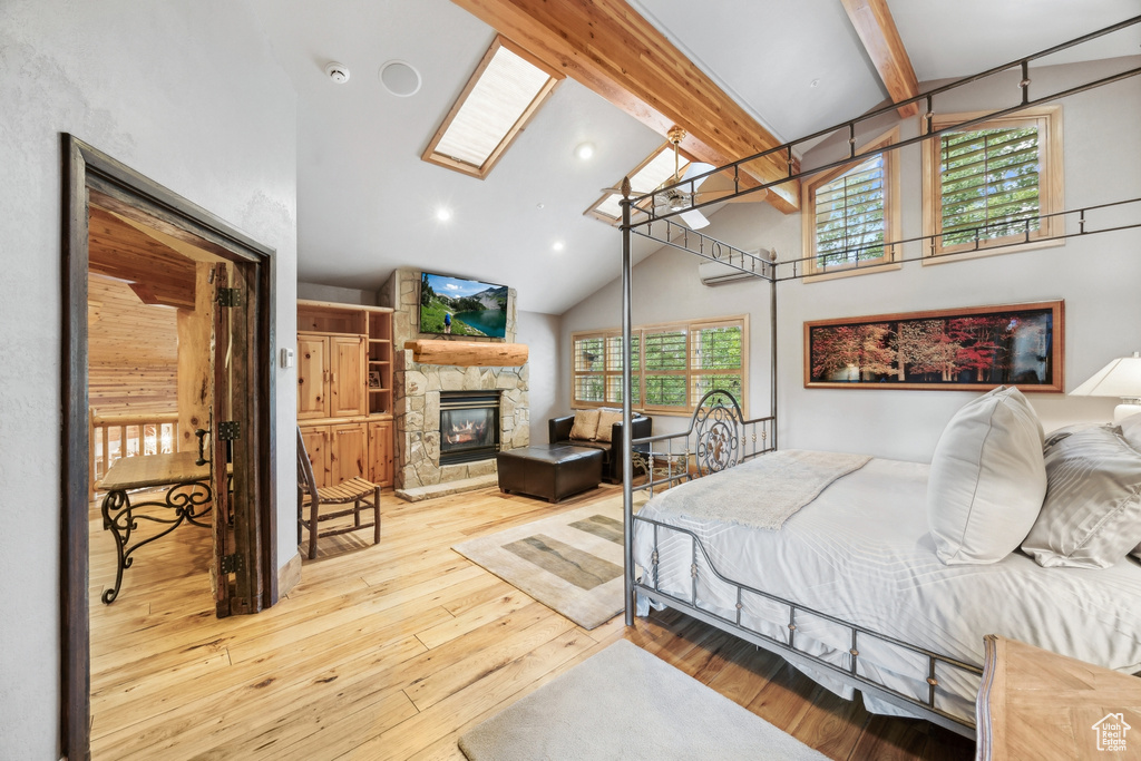 Bedroom featuring high vaulted ceiling, a stone fireplace, beam ceiling, and light wood-type flooring