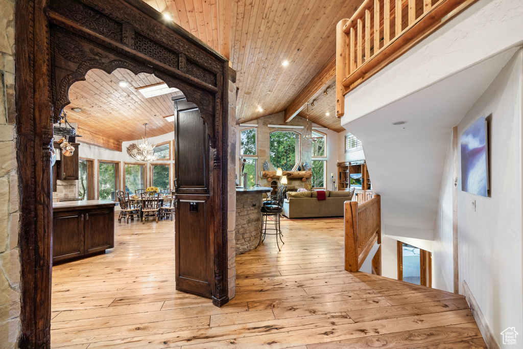 Interior space featuring beam ceiling, light hardwood / wood-style floors, wood ceiling, and an inviting chandelier